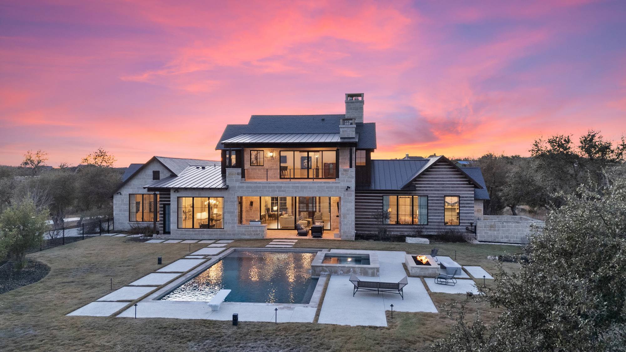 Hill Country stone estate with a pool at sunset in Boot Ranch, Fredericksburg, Texas